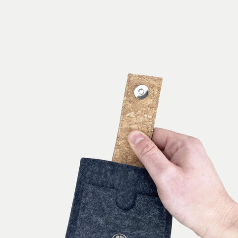 Hand, die einen Korkverschluss hält und eine anthrazitfarbene Handyhülle für das Motorola Moto G86 zieht.